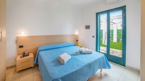 Habitación de hotel con cama, mesita de noche y aire acondicionado.