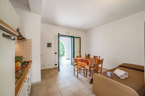 A compact hotel room with a kitchenette, a dining area with a table and chairs, and a bed with a brown headboard. - Beach in 5 min | Pool Access | n.53, Otranto, Italy (Otranto)