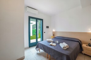 Ein Schlafzimmer mit Bett, Nachttisch, Fenster und Klimaanlage.