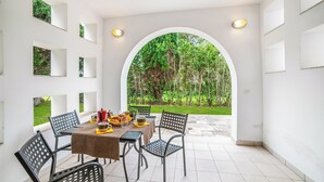 A covered patio with a table set for dining, chairs, and a view of a garden through an archway. - Beach in 5 min | Pool Access | n.51, Otranto, Italy (Otranto)