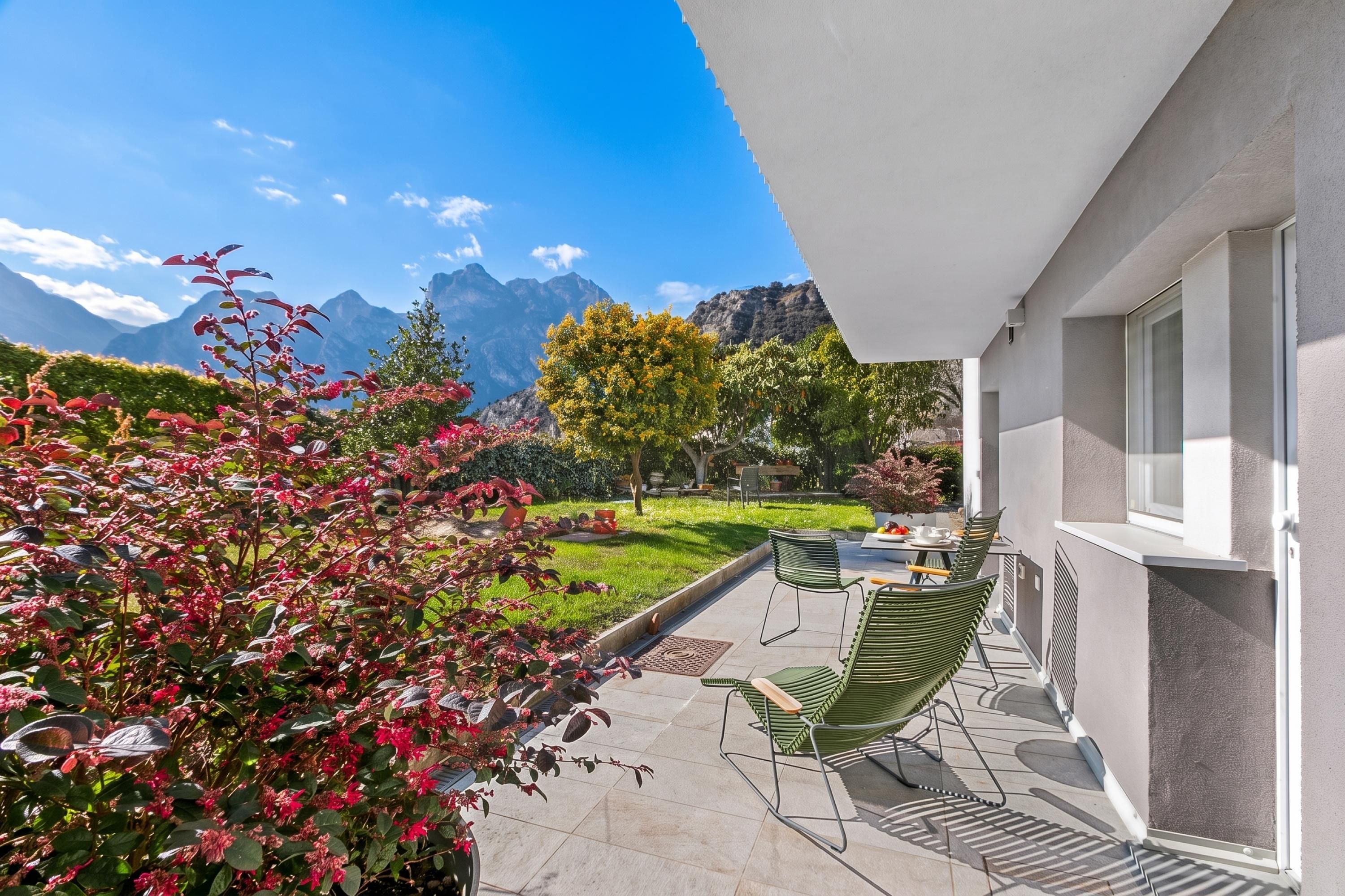 A patio with outdoor furniture, a view of mountains, and a well-maintained garden.