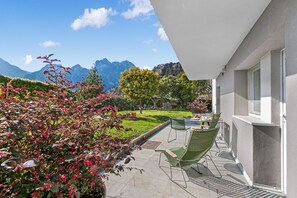 Eine Terrasse mit Gartenmöbeln, Blick auf Berge und ein gepflegter Garten.