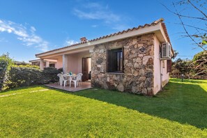 A two-story house with a stone facade, a patio with a table and chairs, and a well-maintained lawn. - Le Case Della Cinta 2 a 300 Mt Dal Mare, San Teodoro, Italy (San Teodoro)