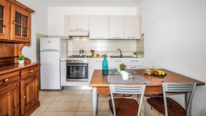 Una cocina con armarios de madera, un refrigerador blanco, una estufa y una mesa de comedor con sillas.
