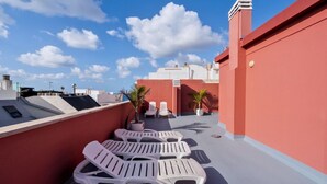 A rooftop terrace with white lounge chairs, potted plants, and a clear blue sky. - GuestReady - Rosamar Playa Canteras II (Las Palmas de Gran Canaria)