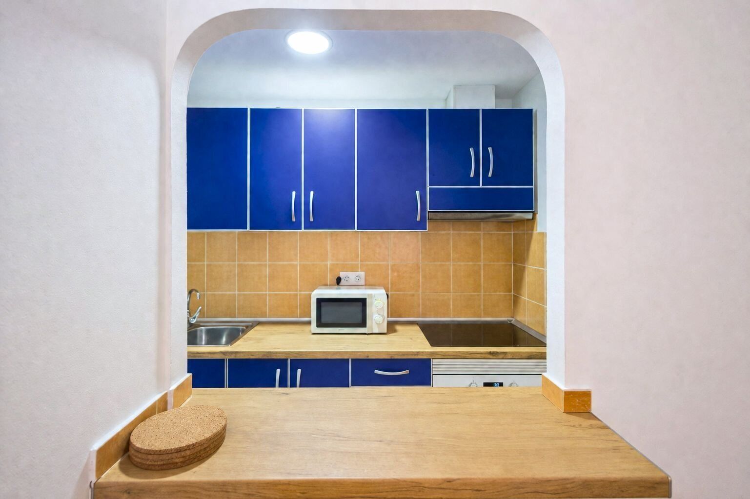 Una cocina con gabinetes azules, un microondas y una encimera de madera.