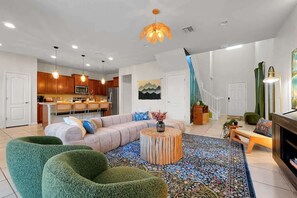 A modern living room with a sofa, green armchairs, a coffee table, and a patterned rug. - Luxury Villa Game Room, Pool & Resort Access (Kissimmee)