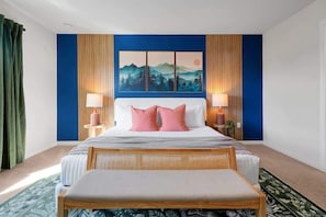 A bedroom with a bed, two bedside lamps, a large painting, and a wooden bench. - Luxury Villa Game Room, Pool & Resort Access (Kissimmee)