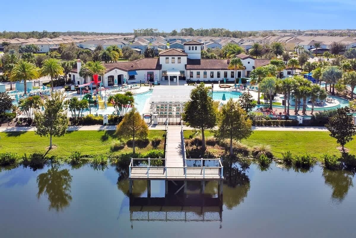 Un resort con piscina central, un muelle sobre el agua y un edificio grande con zona de patio.