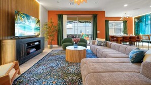 Een moderne woonkamer met een bank, televisie en een eethoek met stoelen en een tafel.