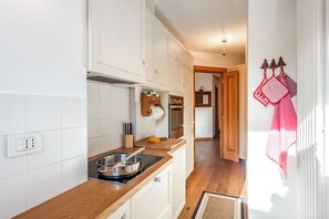 A kitchen with white cabinets, a wooden countertop, a stove, and a cutting board with vegetables. - Charming Apartment Close to Cableway, Pré-Saint-Didier, Italy (Pré-Saint-Didier)