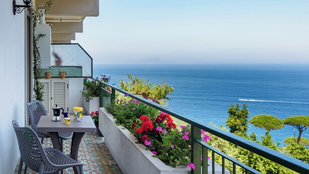 A balcony with a table, chairs, and a view of the sea. - Vervece House (Massa Lubrense)