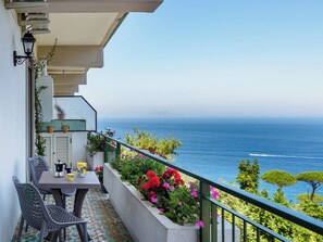Un balcon avec une table, des chaises et une vue sur la mer.