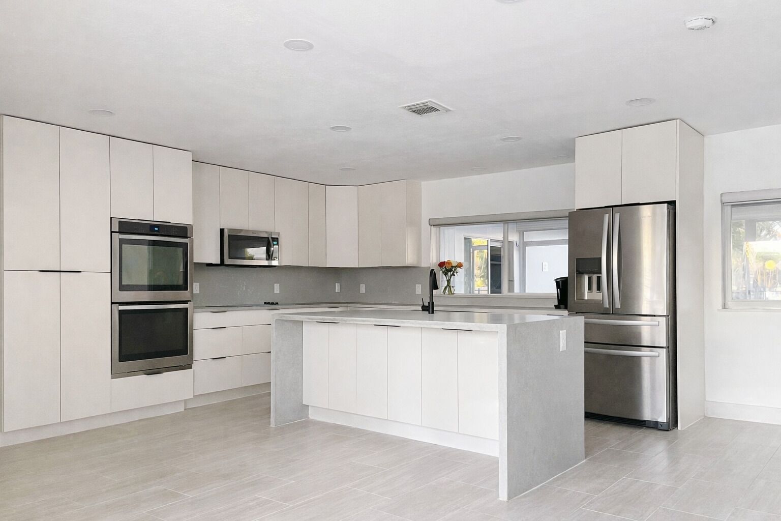 Een moderne keuken met witte kasten, roestvrijstalen apparatuur en een groot eiland.