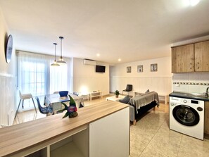 A modern kitchen with a washing machine, a dining area with a table and chairs, and a living area with a sofa. - SR Mar Bonita 2BDR La Carihuela Beach (Torremolinos)