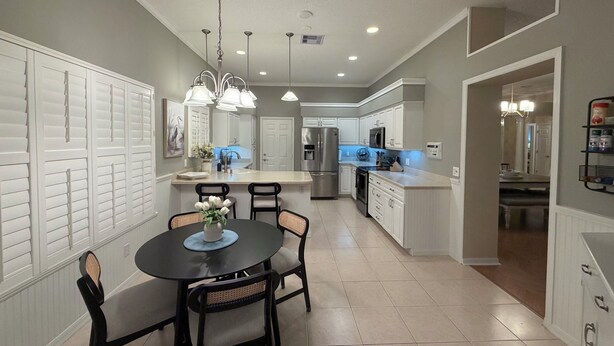A modern kitchen with white cabinetry, a central island, and pendant lighting. - Welcome to Coastal Retreat 
at Palo Alto! (The Villages)