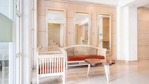 Una hall d'albergo moderna con una panca bianca, un tavolino e uno specchio.