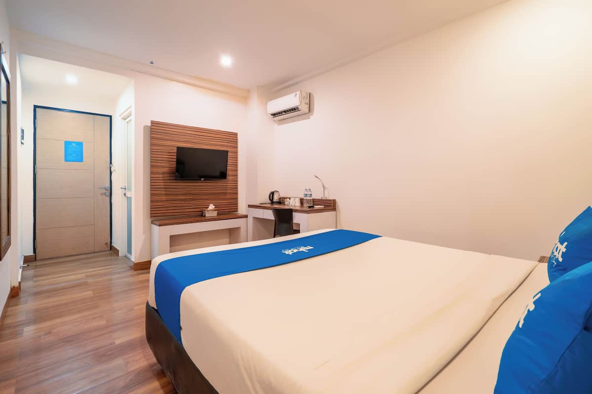 Ein Hotelzimmer mit Bett, Schreibtisch, Fernseher und Klimaanlage.