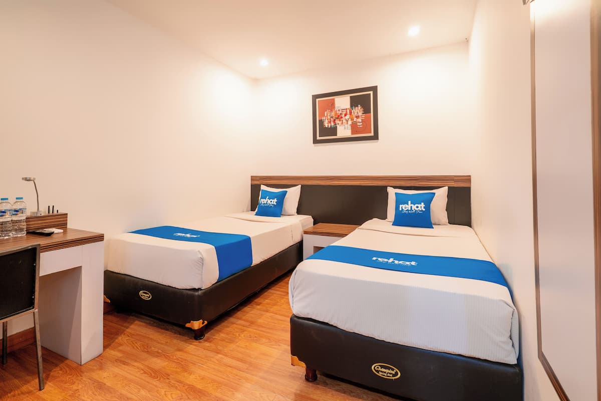Ein Hotelzimmer mit zwei Betten, einem Schreibtisch und einem kleinen Tisch.