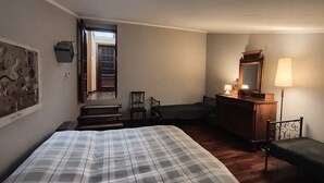 A bedroom with a bed, a dresser, a chair, a desk, a lamp, and a staircase leading to an outdoor area.