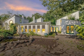 A modern house with a stone pathway, a pond, and a garden.
