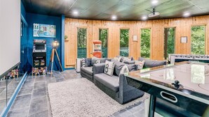 A room with a wooden wall, a sofa, a foosball table, and a projector screen. - !Poconos Hidden Villa de’Casablanca Pool+Spa Creek (Stroudsburg)