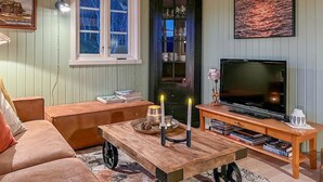 A cozy living room with a sofa, a coffee table with candles, a TV, and a bookshelf. - Amazing home in Sømna with WiFi (Sømna)