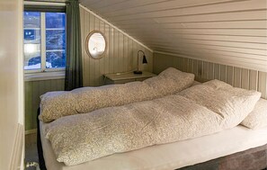 Une chambre à coucher avec un lit, une table de chevet, un miroir et une fenêtre donnant sur des arbres.
