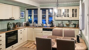 A kitchen with a dining area, wooden cabinets, a stove, and a chandelier. - Amazing home in Sømna with WiFi (Sømna)