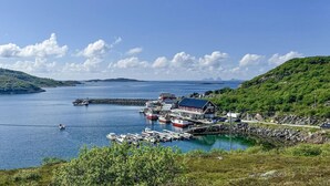 A coastal harbor with boats, a red building, and a clear sky. - Beach front home in Nordnesøy with house a panoramic view (Nordnesøy)