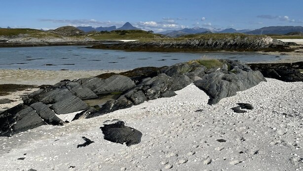 A rocky shoreline with a clear view of distant mountains and a calm body of water. - Beach front home in Nordnesøy with house a panoramic view (Nordnesøy)