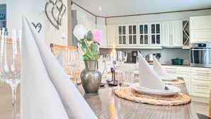 A dining table set with white napkins, a vase with flowers, and a candle. - Beach front home in Nordnesøy with house a panoramic view (Nordnesøy)