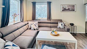 A modern living room with a sectional sofa, a coffee table, and a framed picture on the wall. - Beach front home in Nordnesøy with house a panoramic view (Nordnesøy)