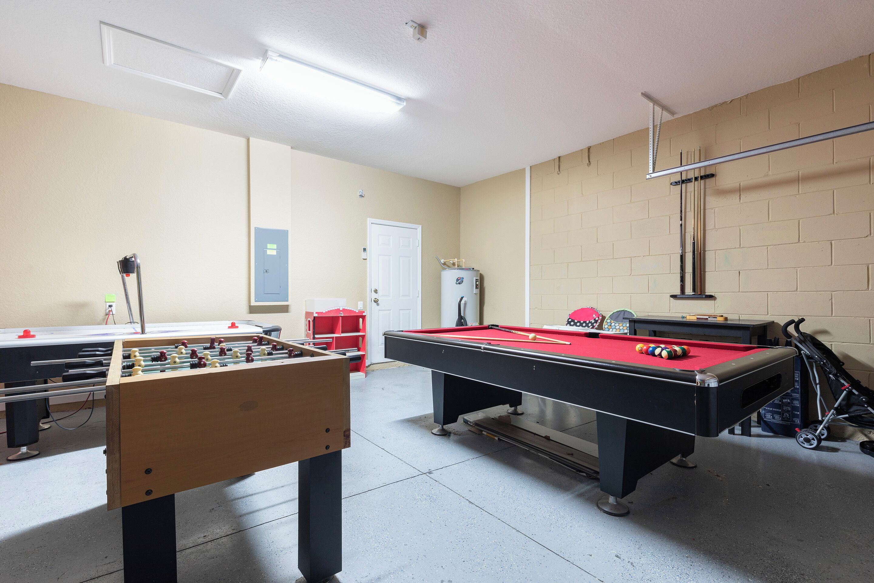 A billiards room with a pool table, a foosball table, and a dartboard.