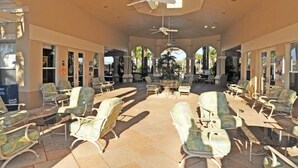 A covered outdoor seating area with chairs and tables, a ceiling fan, and a view of the street. - Windsor Hills Resort (Kissimmee)