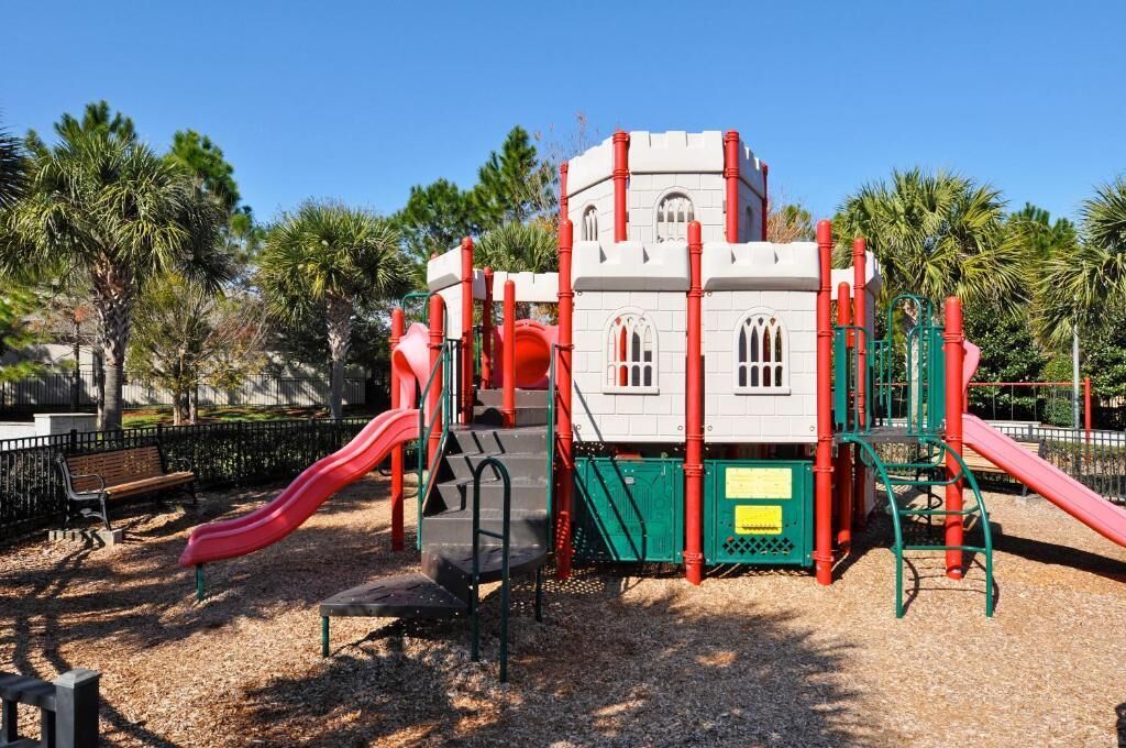 Ein Spielplatz mit einer Burgenähnlichen Struktur, Rutschen und einer Sitzbank.