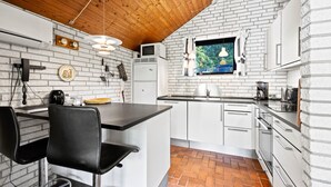 A kitchen with white cabinets, a brick floor, a wooden ceiling, and a hanging light fixture. - 3 bedroom amazing home in Nørre Nebel (Nørre Nebel)