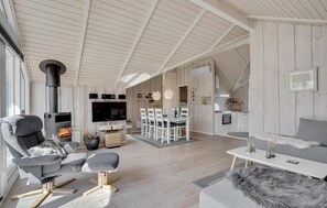 Ein geräumiger Wohnbereich mit Kamin, Esstisch und einer Küche im Hintergrund.