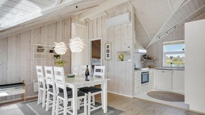 Een moderne keuken met witte kastjes, een eethoek met een glazen tafel en uitzicht op de omgeving.