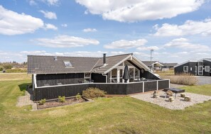 Et moderne hus med saddeltag, en overdækket terrasse og et lille haveområde.
