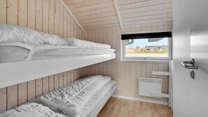 Een slaapkamer met stapelbedden, houten wanden, een raam met uitzicht en een witte deur.