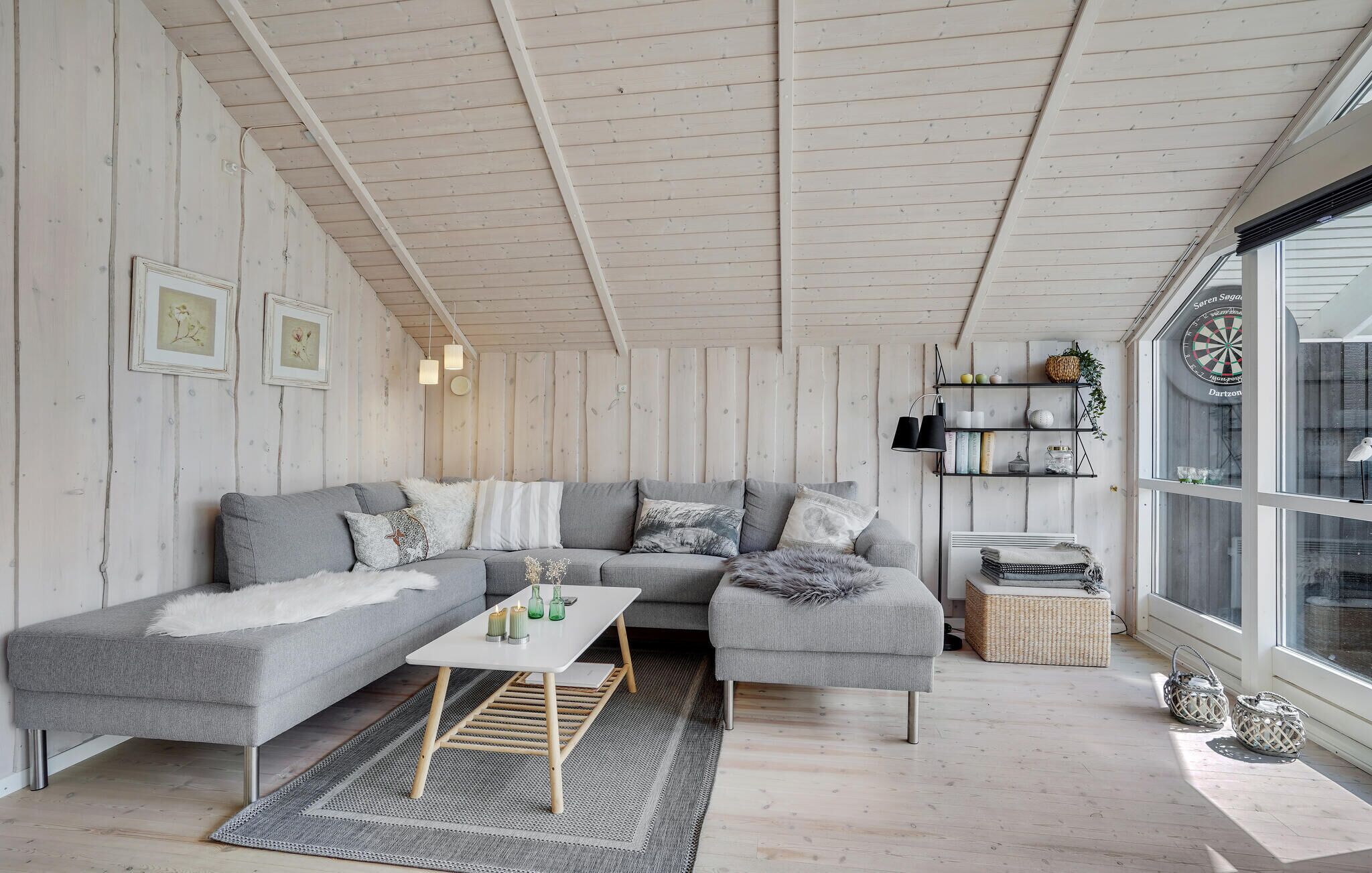 A modern living room with a grey sectional sofa, a white coffee table, and a wooden ceiling.