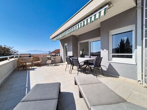 Una terrazza sul tetto con poltrone, un tavolo e sedie.