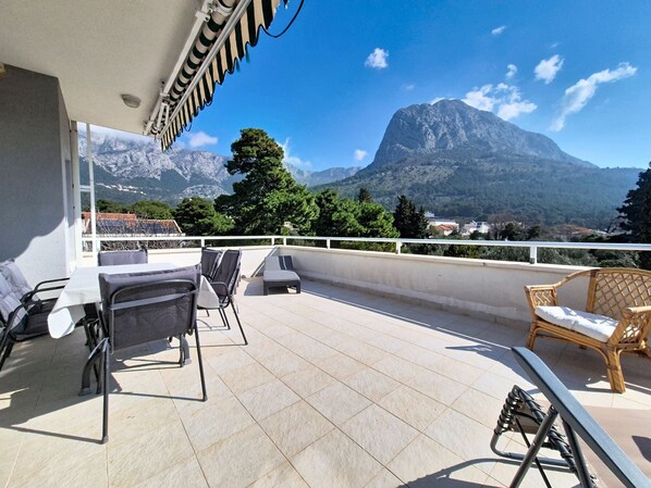 Una terrazza con mobili da esterno, vista sulle montagne e cielo sereno.