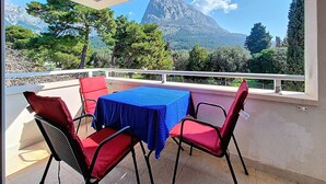 A balcony with a table and chairs, a mountain view, and a railing.