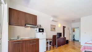 A compact kitchen with wooden cabinets, a microwave, and a refrigerator.