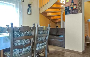 A dining area with a wooden table and chairs, a sofa, a staircase, and a wall with a framed picture. - 3 bedroom pet friendly home in Jezierzany (Jezierzany)