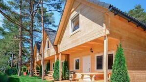 Una cabana de fusta amb un porxo, una zona de menjador i una petita zona de jocs.