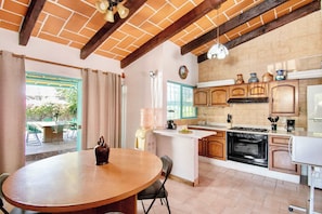 A kitchen with a brick ceiling, wooden cabinets, a central island, and a dining area with a table and chairs.
