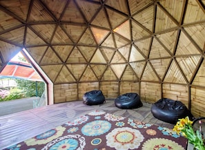 A room with a geometric wooden ceiling, two black bean bags, and a colorful patterned rug.